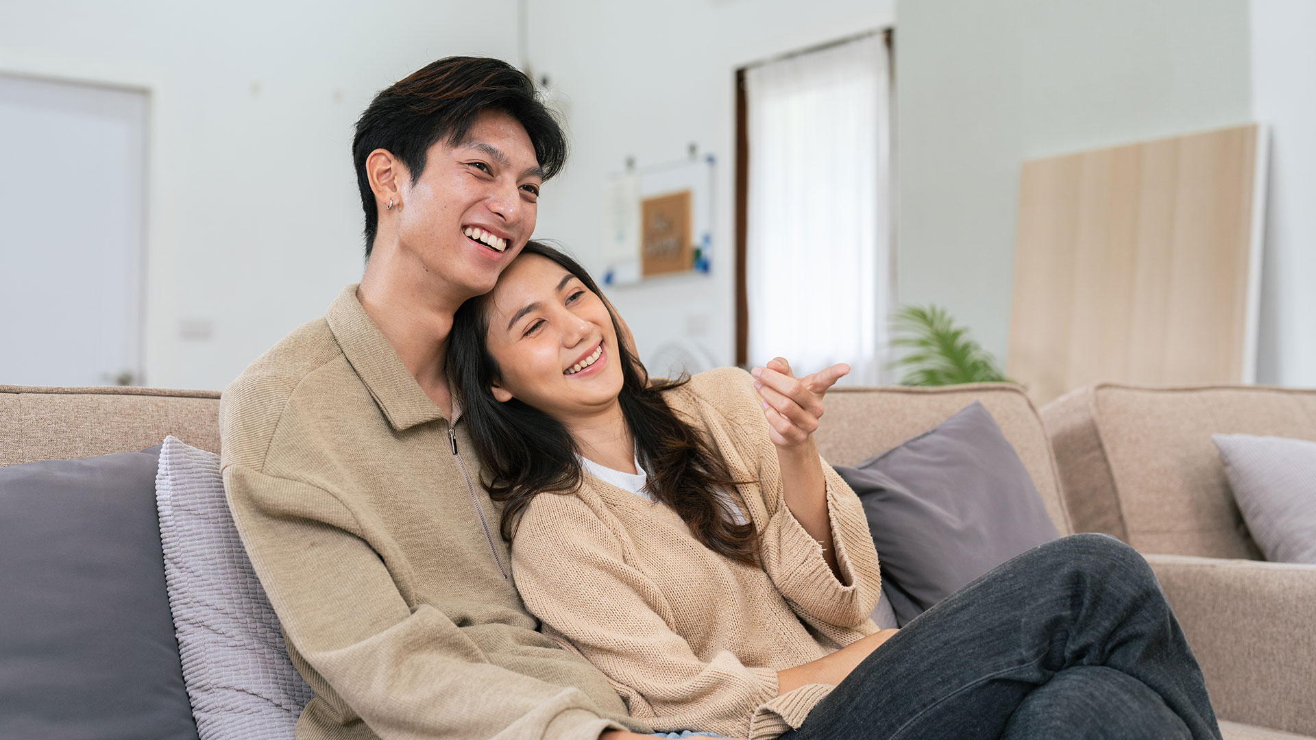 Common law partners smiling together on the couch in their home